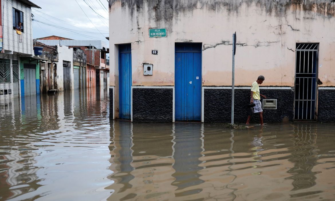 A person walks through the water along a street during floods caused by heavy rain in Itajuipe, Bahia state, Brazil December 27, 2021. REUTERS/Amanda Perobelli